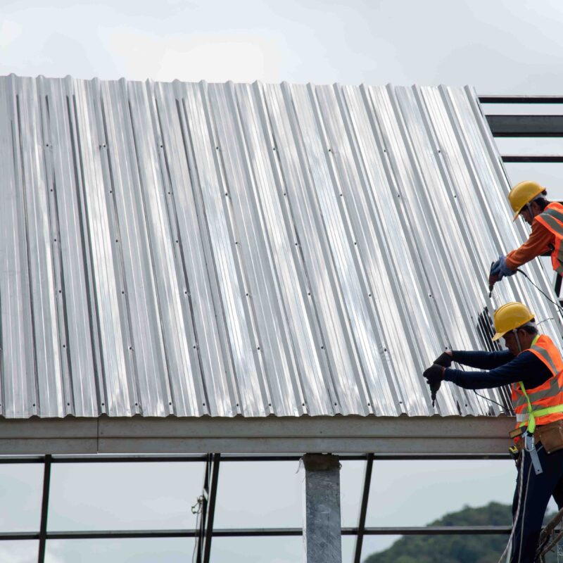 Workers attaching sheet metal to a roof.